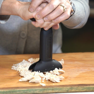dbChopper in use chopping cooked shredded chicken on a wooden cutting board